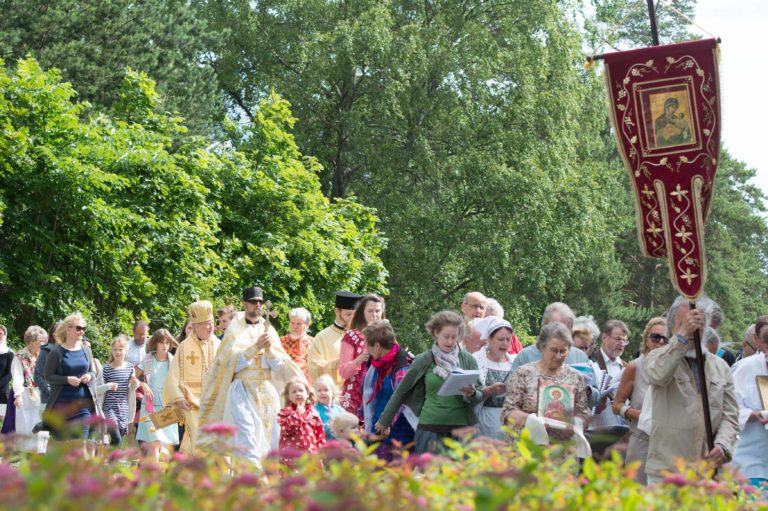 Joukko ihmisiä vaeltaa ristisaatossa kirkkolipun perässä HAngon 120-vuotisjuhlapraasniekassa.