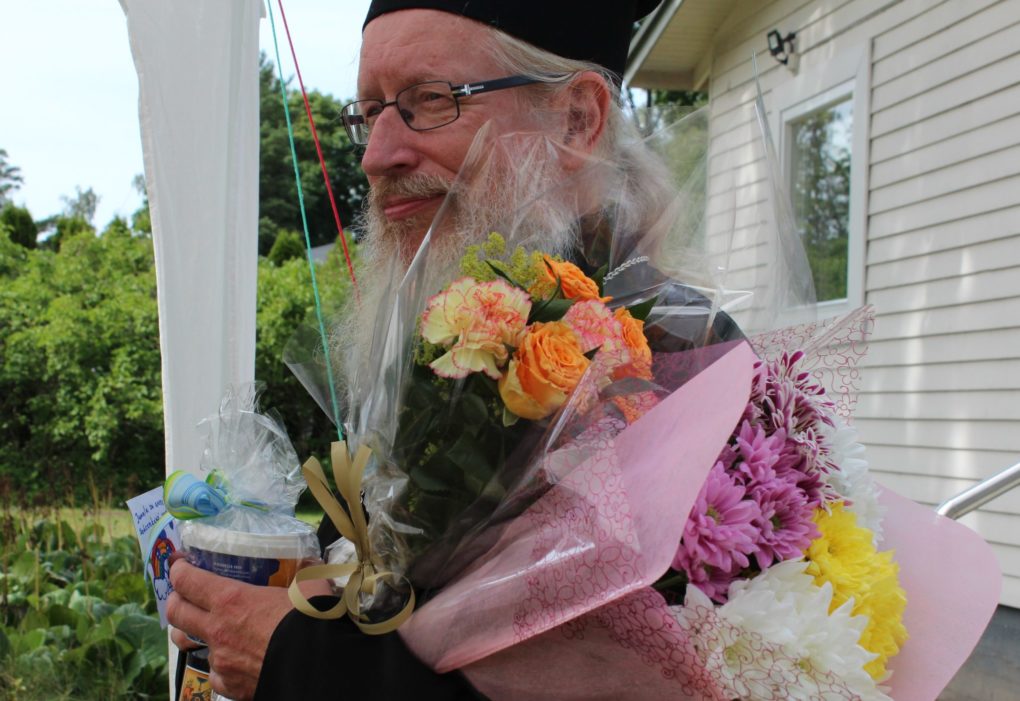 Ortodoksinen pappi, jolla on kukkia käsissään.