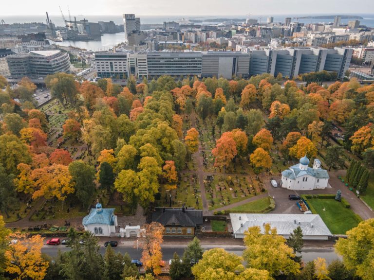 Yläilmoista otettu kuva, jossa näkyy koko Helsingin ortodoksisen seurakunnan Lapinlahden hautausmaan alue syksyn ruska-aikaan. Oikealla on sinivalkoinen Profeetta Elian kirkko sekä vasemmalla etualalla pieni hautausmaan kappeli. hautausmaan puut ovat keltaisia, vihreitä ja oransseja. Kuva on otettu syksyllä parhaaseen ruska-aikaan. Kuvan yläreunassa näkyy Jätkäsaari ja taustalla vasemmassa yläkulmassa plkottaa meri ja satama.