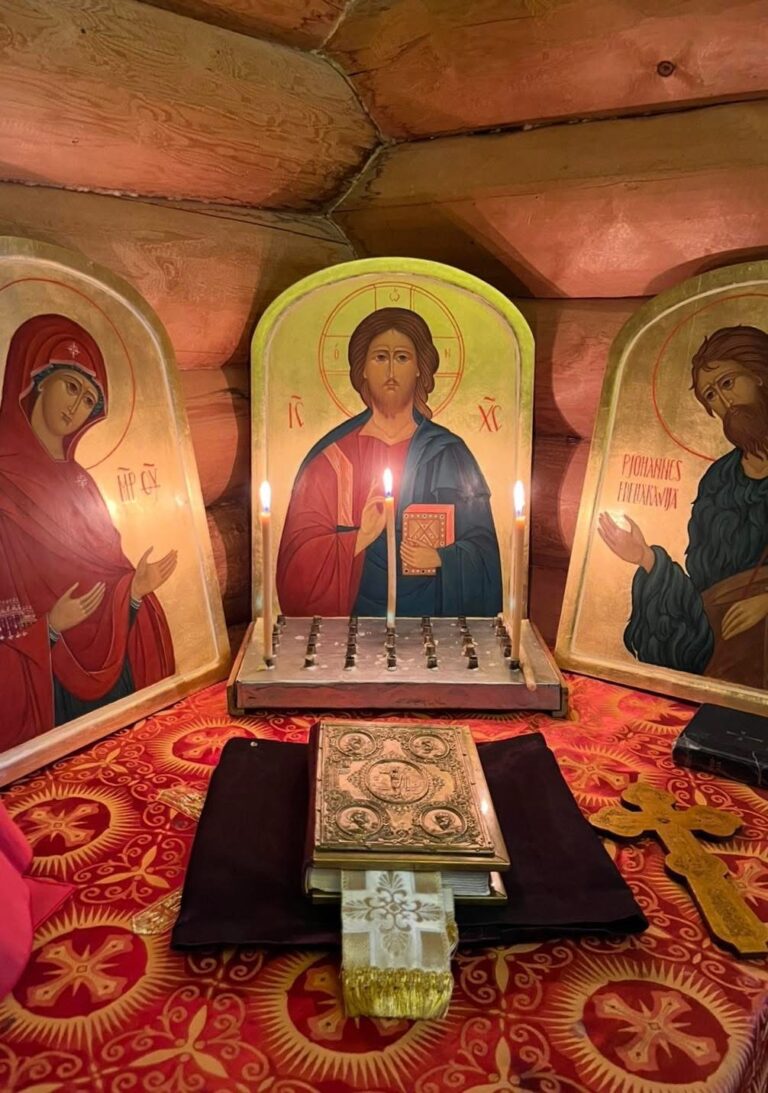 Alttaripöydällä punainen liina, jossa ristikuvioita, ja päällä koristeellinen jumalanpalveluksissa käytettävä Evankeliumikirja sekä papin risti. Pöydän edessä kolme ikonia: keskellä Kristus Kaikkivaltiaan ikoni ja vasemmalla Jumalansynnyttäjä Neitsyt Marian ikoni sekä oikealla Johannes Kastajan ikoni. Jeesuksen Kristuksen ikonin edessä kolme palavaa tuohusta.