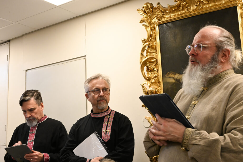 Kolme miestä laulaa karjalaisissa perinneasuissa. 